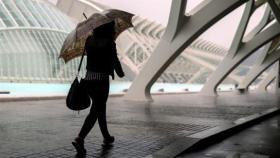 Una persona se resguarda de la lluvia en la Ciudad de las Ciencias de Valencia.