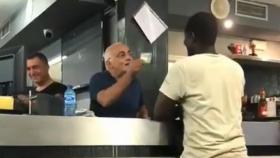 Un camarero arenga a un inmigrante.