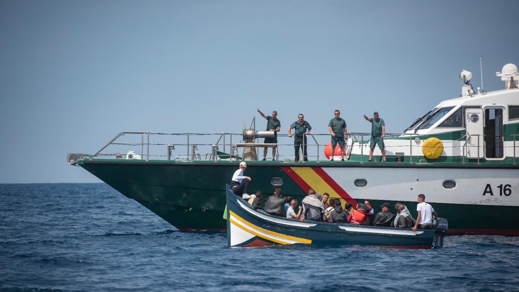Patrullera de la Guardia Civil con varios  agentes a bordo dando indicaciones a los tripulantes de una patera en aguas del Estrecho.