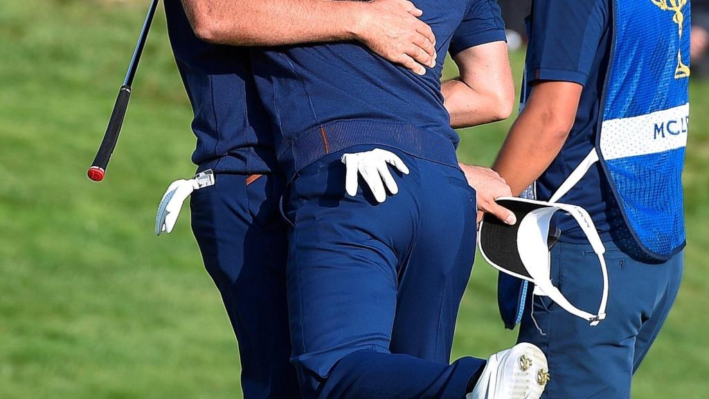 El norirlandés del equipo europeo Rory McIlroy (c) y el inglés Ian Poulter (izda) celebran su victoria