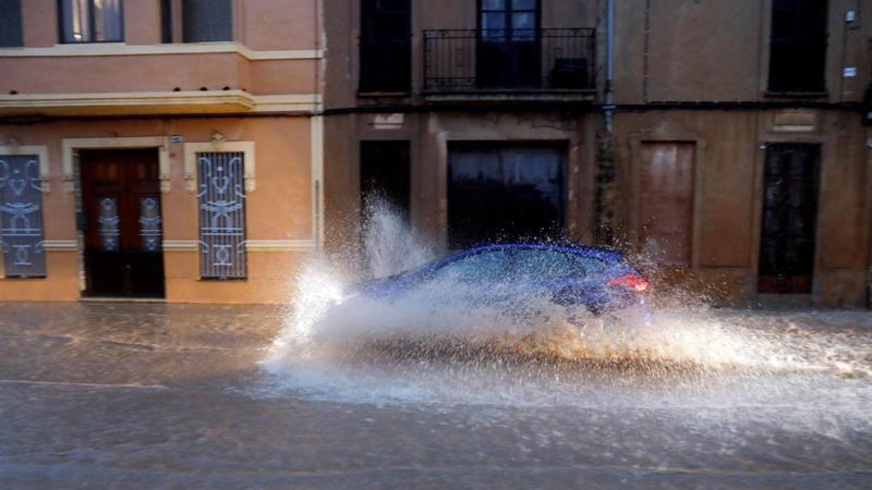 Un vehículo circula por una calle anegada de Valencia.