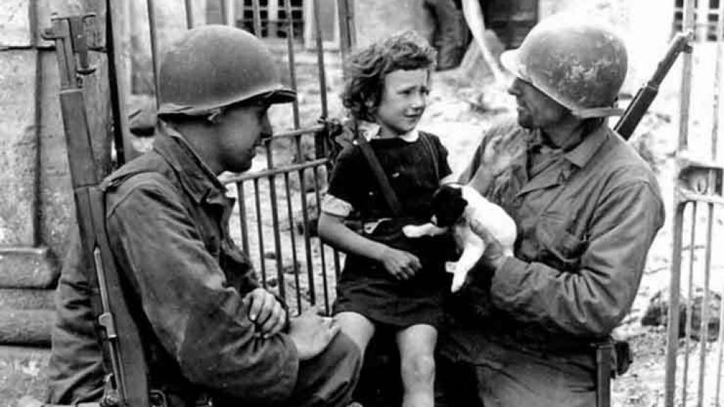 Dos soldados tratan de consolar a una niña herida durante la II Guerra Mundial.