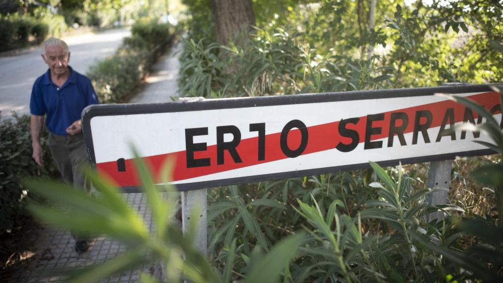 Un hombre camina por delante de la señal de salida de Puerto Serrano (Cádiz).