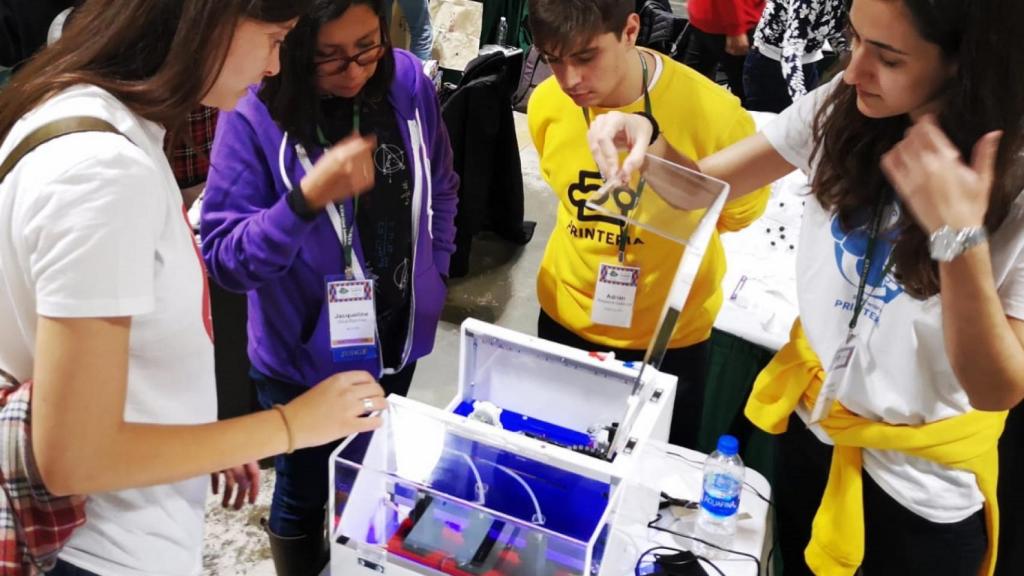 Cuatro de los alumnos de la UPV con la máquina de Printeria en el iGEM.