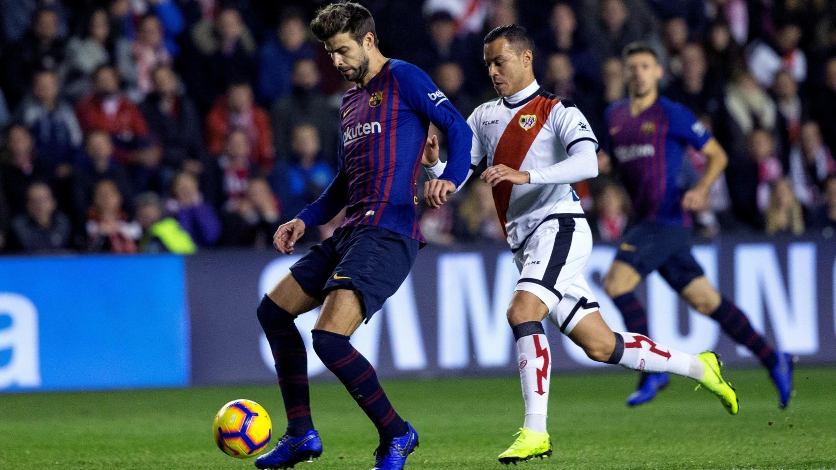 Piqué juega el balón ante la presencia de Raúl de Tomás