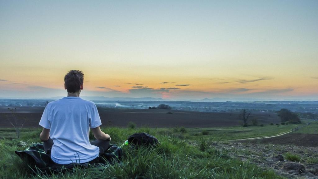 Un joven realiza su sesión diaria de meditación para estar feliz de verdad.