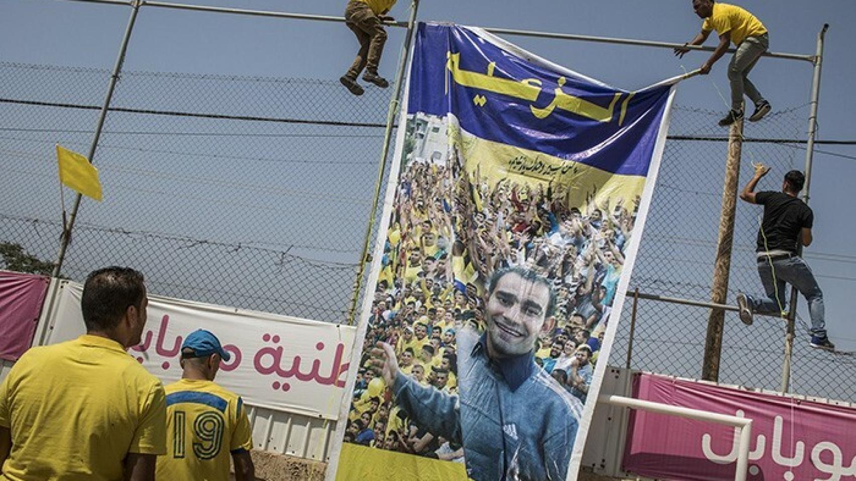 Aficionados del Markaz Tulkarem cuelgan una pancarta conmemorativa en el estadio. Foto: goteo.org/project/markaz-tulkarem-el-retorno-del-equipo-refugiado