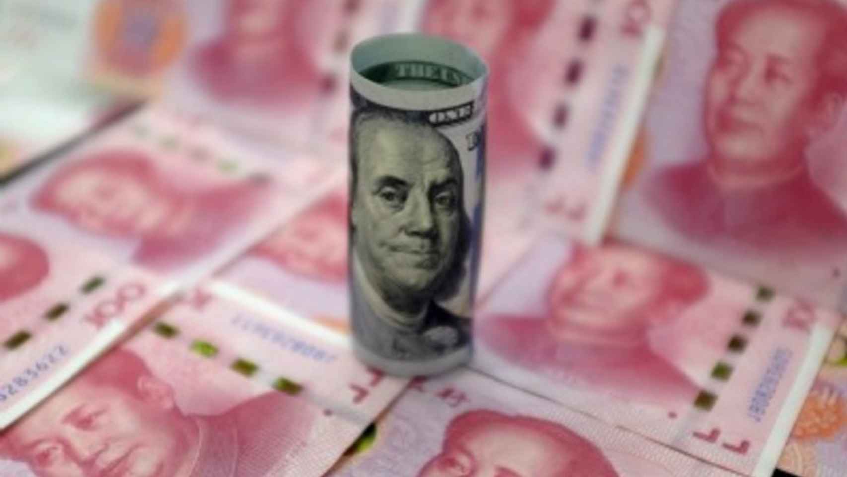 Un billete de dólar sobre una plancha de billetes de yuanes chinos.