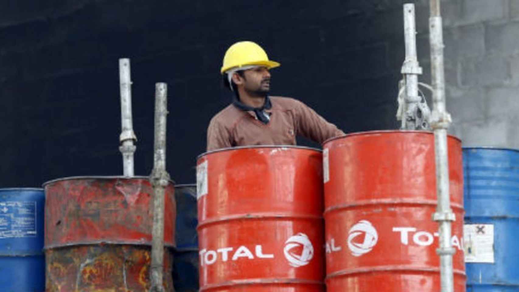 Un operario con barriles de petróleo en una refinería.