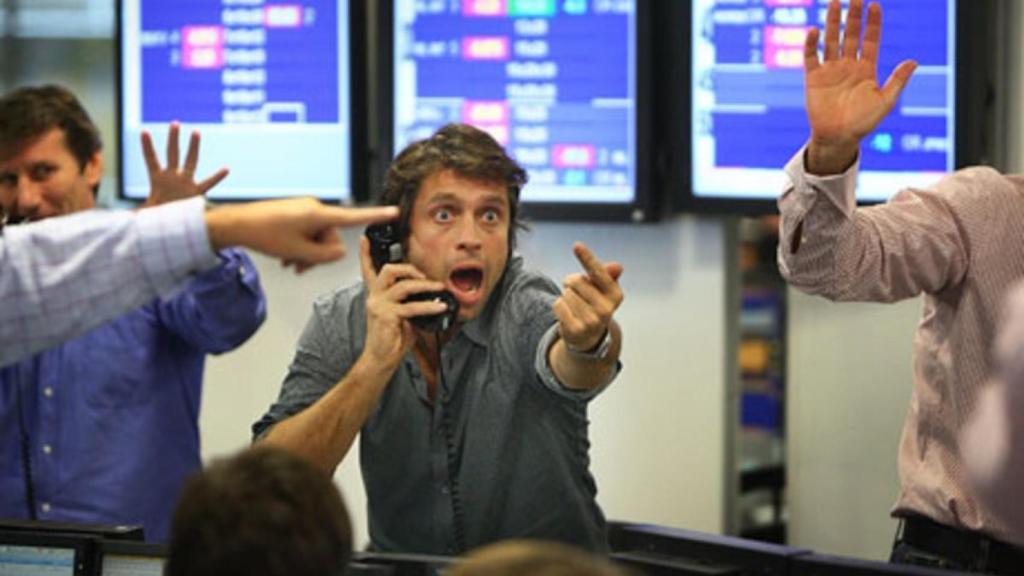 Varios brókeres con gesto de entusiamo en una sala de negociación de valores.