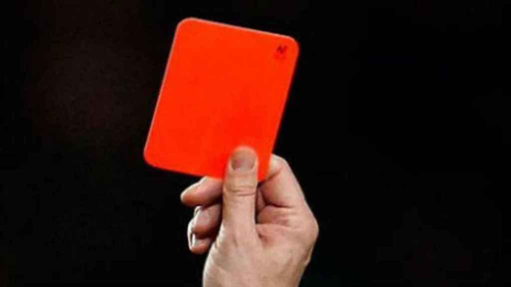 Un árbitro muestra una tarjeta roja.