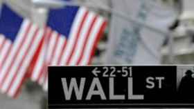Un cartel de Wall Street delante de unas banderas de EEUU.