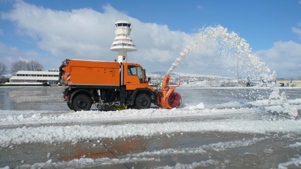 Imagen de un vehículo quitando la nieve acumulada en la pista del aeropuerto