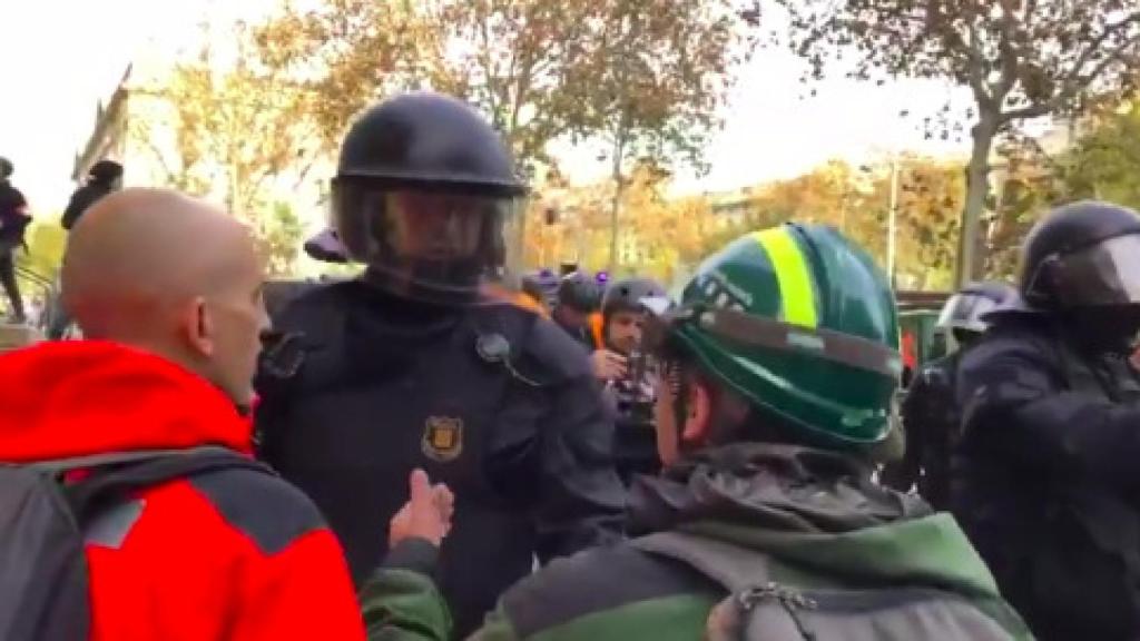 El mosso hablando con un guardia forestal que pretendía romper el cordón policial