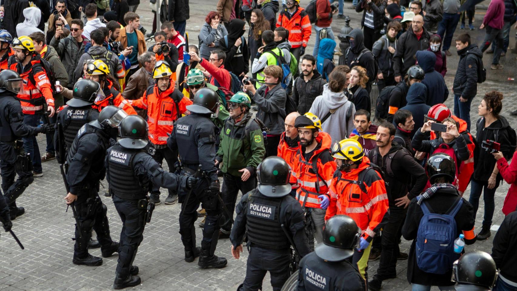 Un grupo de miembros de Bombers per la República monta un cordón entre los manifestantes de los CDR y los Mossos