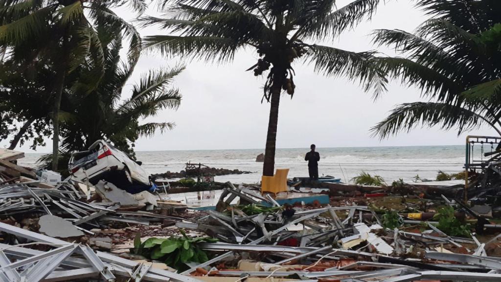 Un hombre permanece de pie entre las ruinas de la playa Carita en Pandeglang.