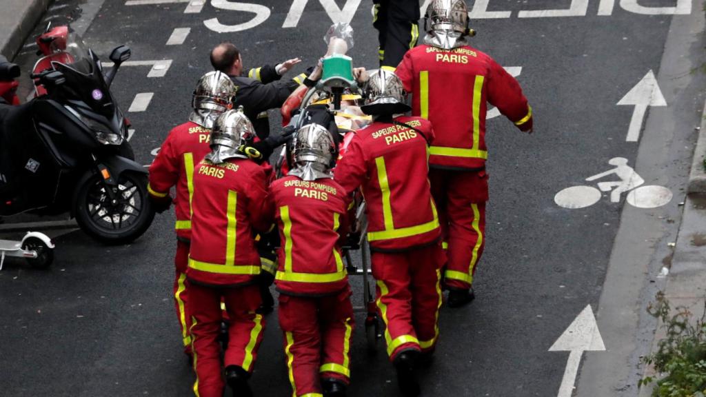 Bomberos asisten a una víctima en la calle de la explosión.