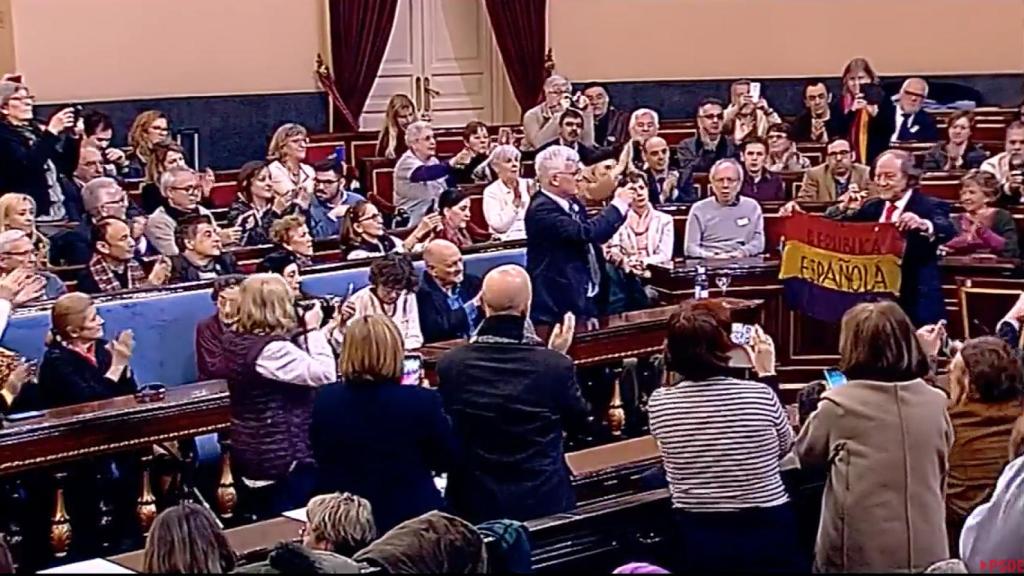 Uno de los asistentes al acto muestra una bandera histórica de la república.