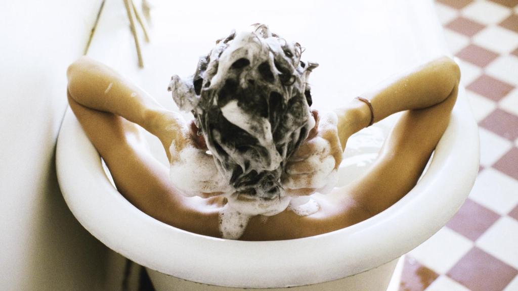 Una señorita lavándose el pelo en su bañera.