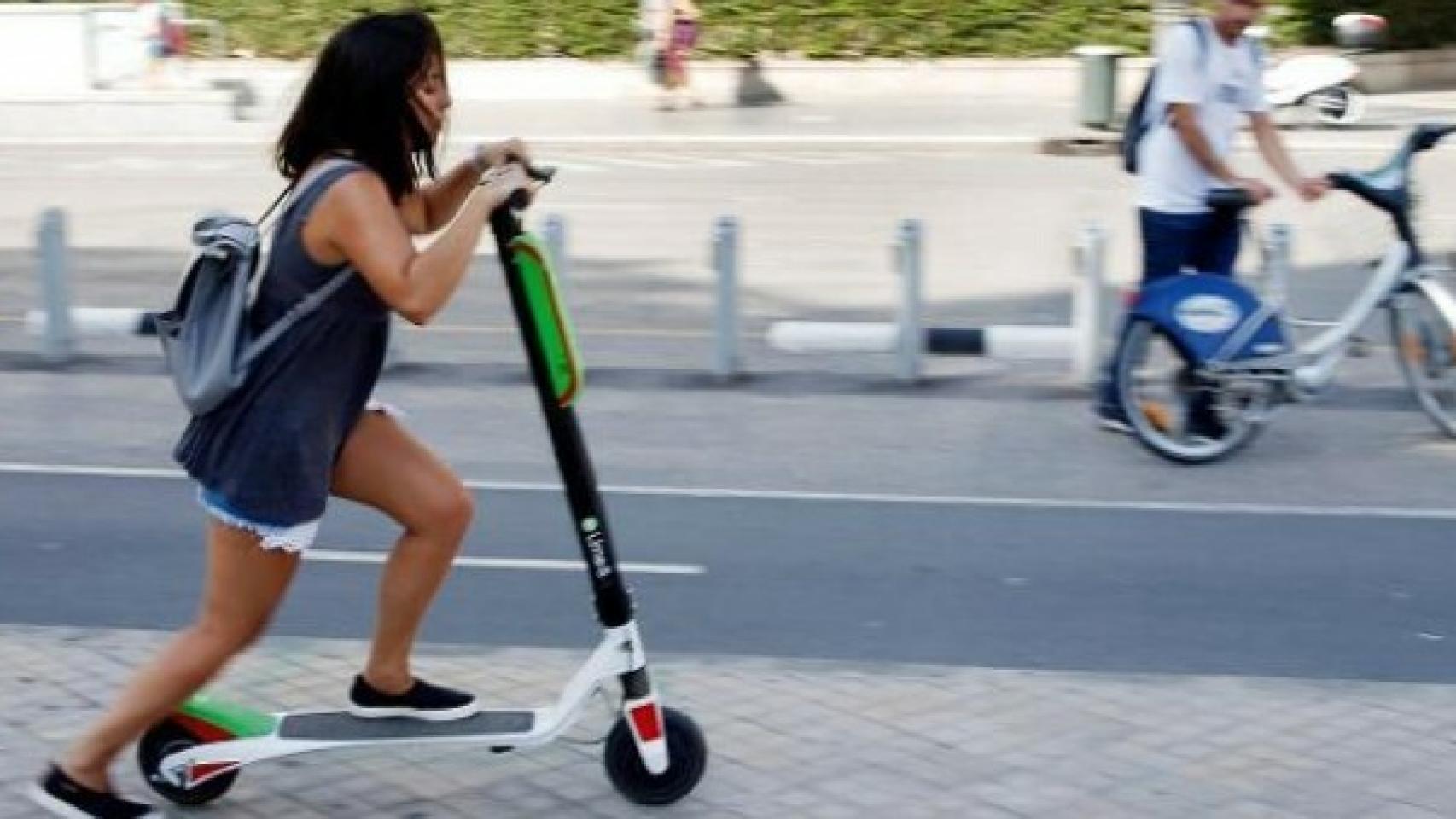 Joven circulando con patinete por la acera