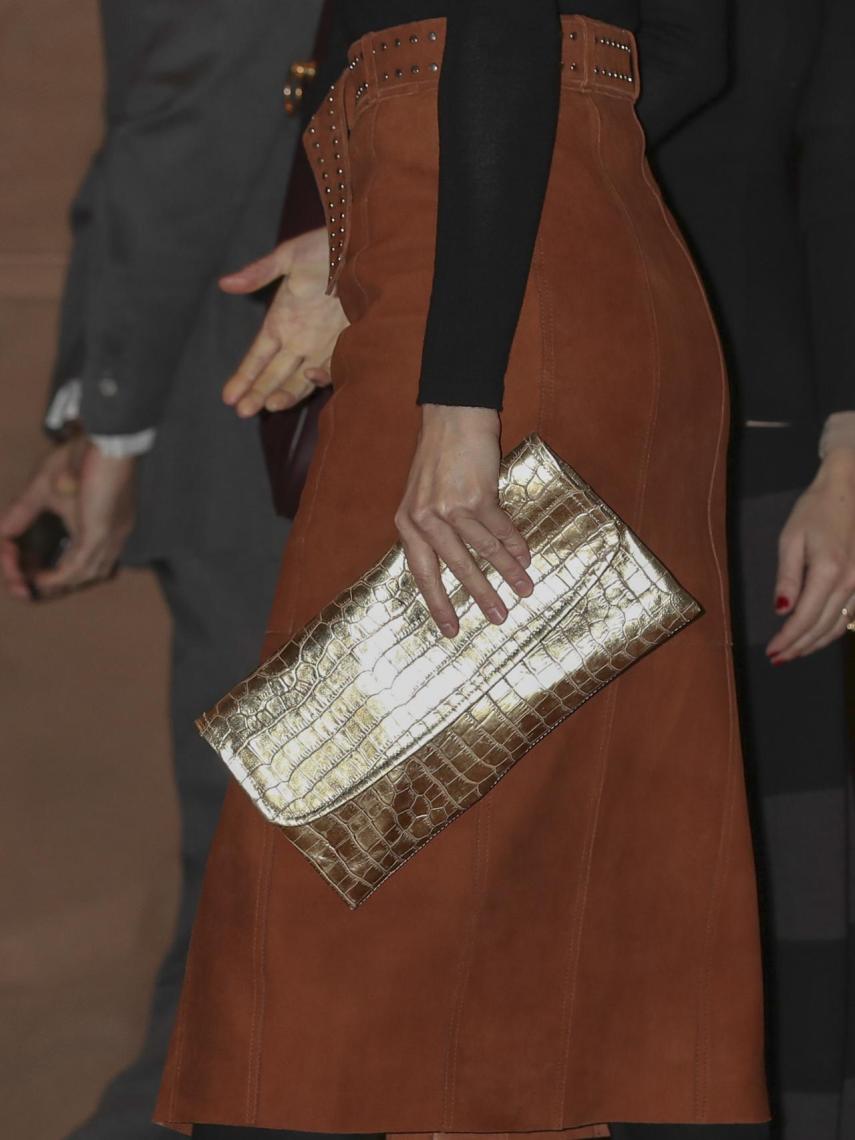 La reina Letizia con cartera de mano dorada.