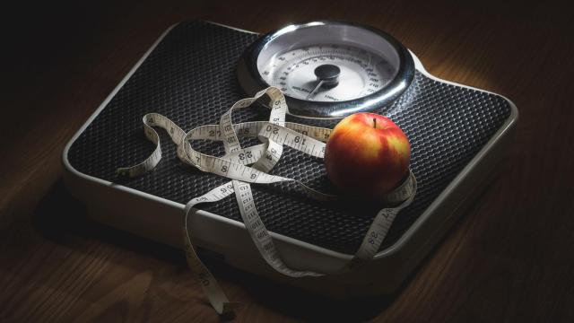 Una manzana y una cinta métrica sobre una báscula.