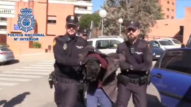 El detenido, esposado y escoltado por agentes de la Policía Nacional.