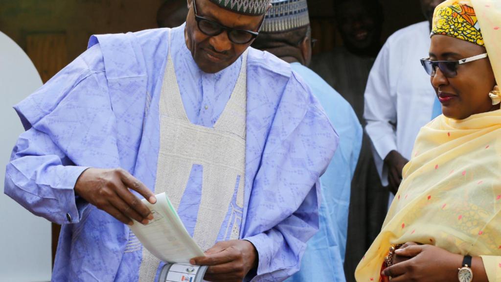 El presidente nigeriano Muhammadu Buhari, acompañado por su esposa Aisha Buhari, emite su voto.