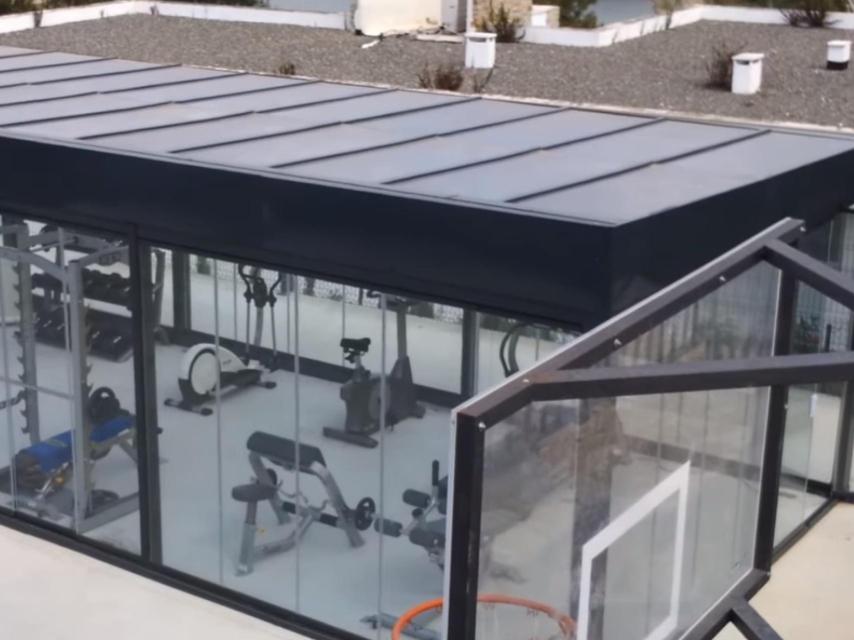 Un sencillo gimnasio con todo tipo de máquinas en el exterior de la casa y protegido para la lluvia.