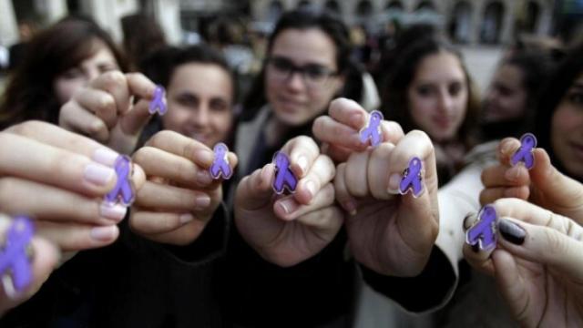 Varias jóvenes muestran el lazo morado, símbolo de la lucha contra la violencia machista.