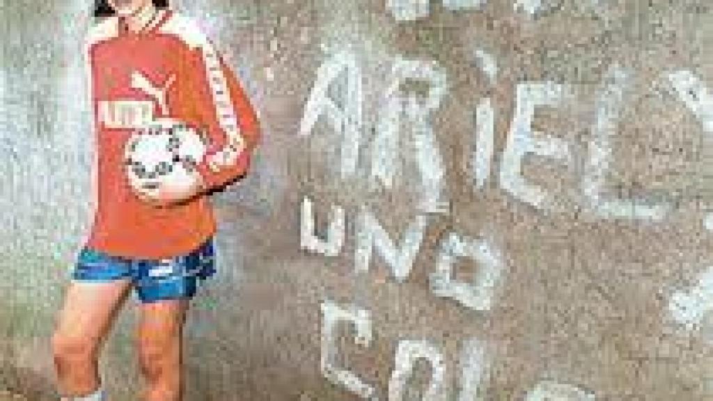 El pequeño Ariel, con 14 años y delante de una pintada que lo comparaba con Maradona