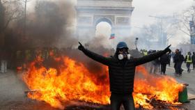Un manifestante se para frente a una barricada en llamas durante la manifestación de los 'chalecos amarillos' en París.