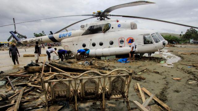 Varias personas se paran cerca de un helicóptero tras las inundaciones en Papúa, Indonesia.