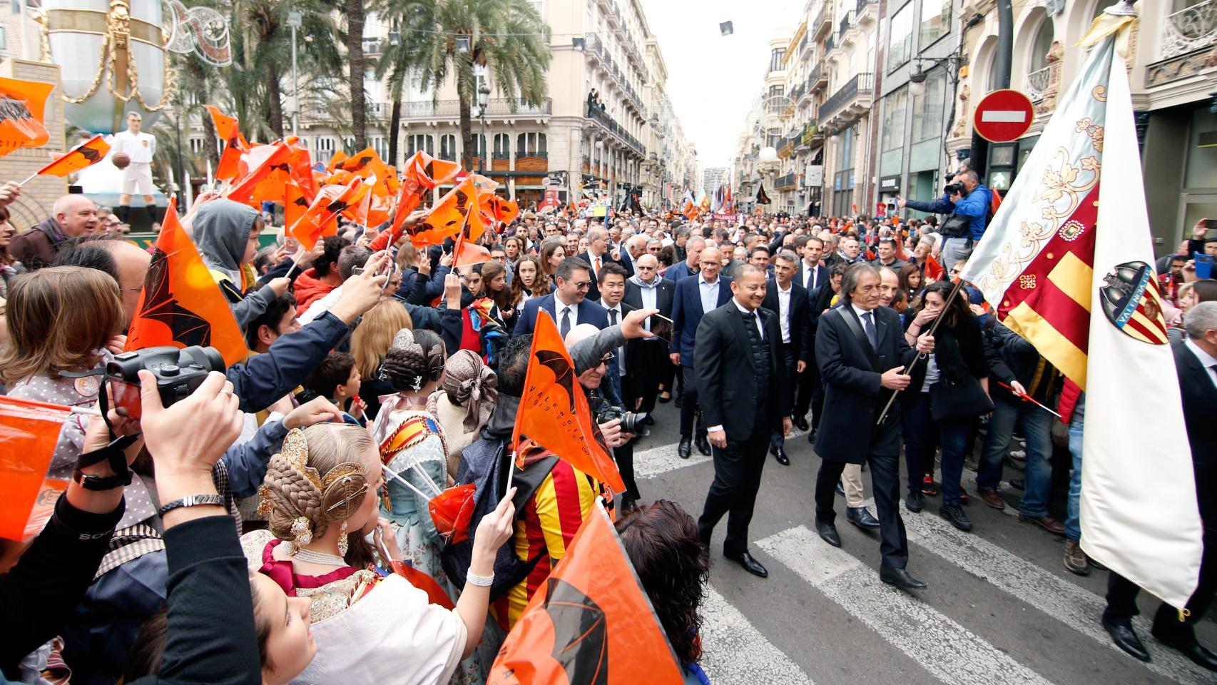 Ricardo Arias, exjugador del Valencia CF, acompañado por el presidente del club, Anil Murthy, portando la bandera del club durante la marcha cívica por el centenario de su fundación