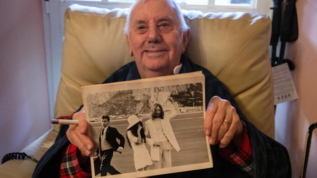 Charlie Galliano mostrando una foto en la que aparece (a la izquierda con corbata), junto a Lennon y Ono.