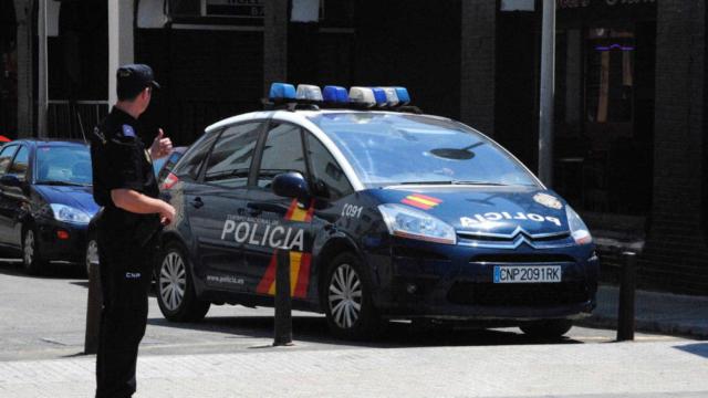 Una imagen de un agente  frente a un coche de la Policía Nacional.