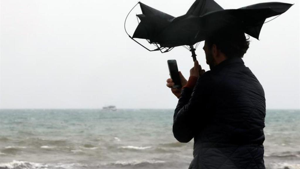 Una persona hace una fotografía en la Playa de la Malvarrosa de Valencia bajo la lluvia y el fuerte viento. Juan Carlos Cárdenas. EFE.