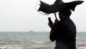 Una persona hace una fotografía en la Playa de la Malvarrosa de Valencia bajo la lluvia y el fuerte viento. Juan Carlos Cárdenas. EFE.