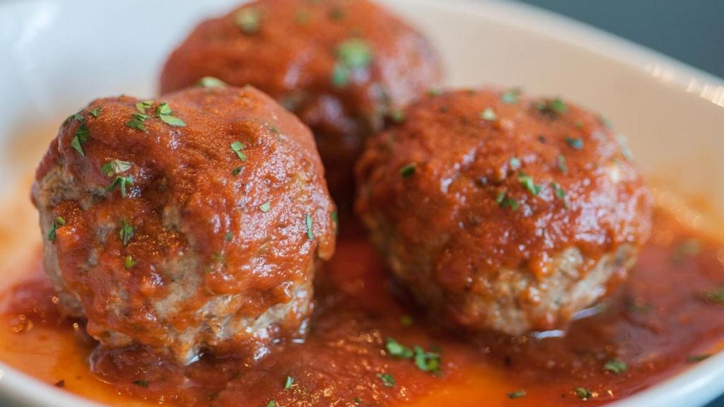 Un plato de albóndigas con tomate frito.