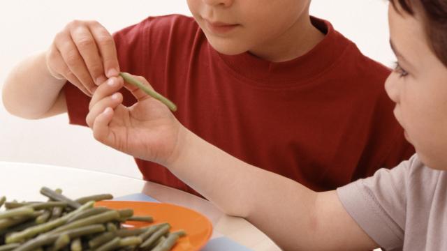 Unos niños comiéndose un plato de judías.