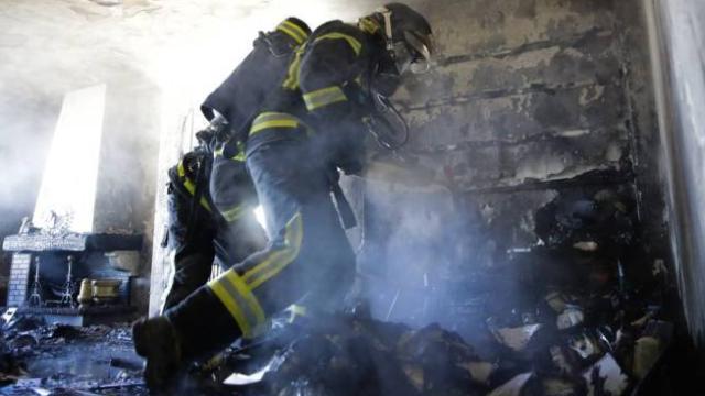 Imagen de archivo de dos bomberos trabajando en un incendio en una casa