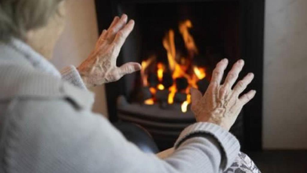 Una persona se calienta las manos ante una chimenea.