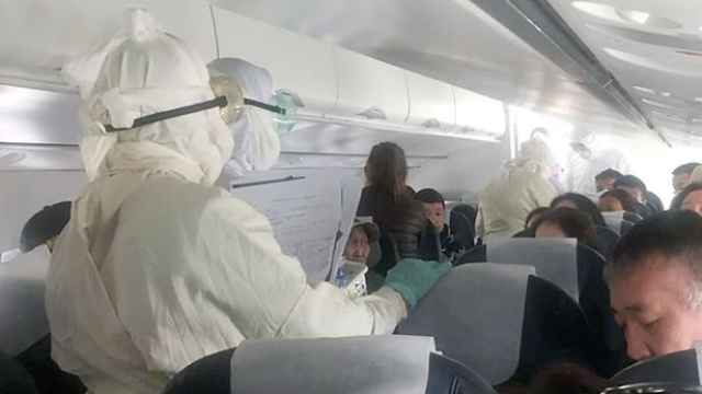 Varias personas con trajes de seguridad en el avión.