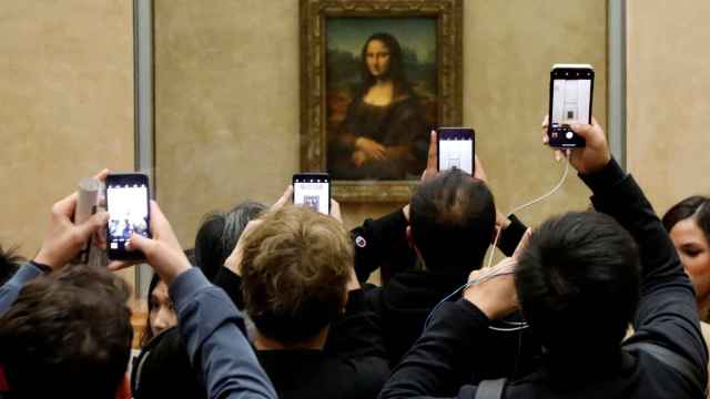 Visitantes del Louvre fotografían a 'La Gioconda' con sus teléfonos móviles.