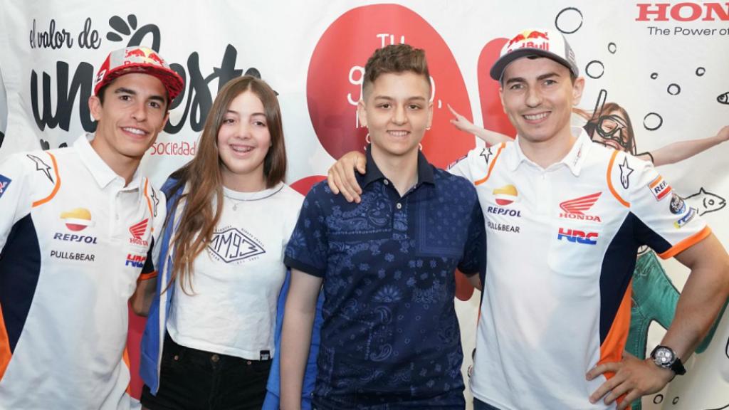 Márquez y Lorenzo posan con dos chavales en la presentación de 'El valor de un gesto'.