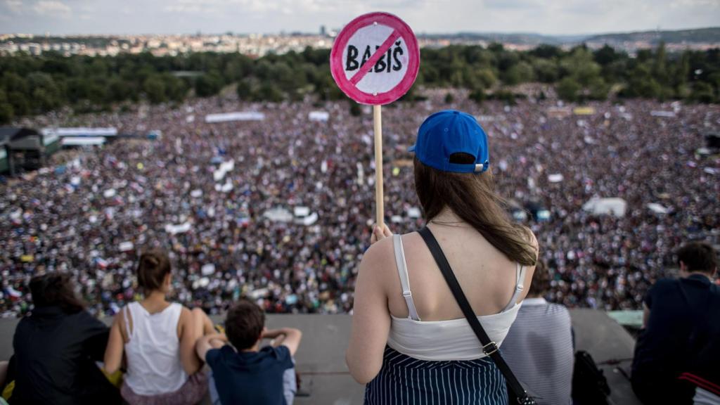 Una joven porta una señal de protesta contra el primer ministro.