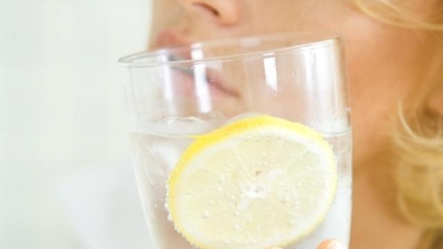 Una mujer sostiene un vaso de agua con gas