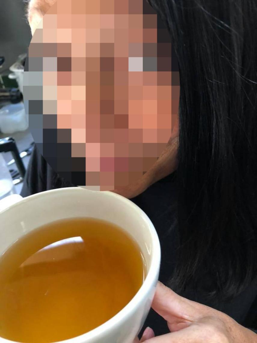 Una señora junto a una taza que contiene su propia orina