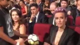 Rapinoe le entrega el balón firmado al niño sin mirarle