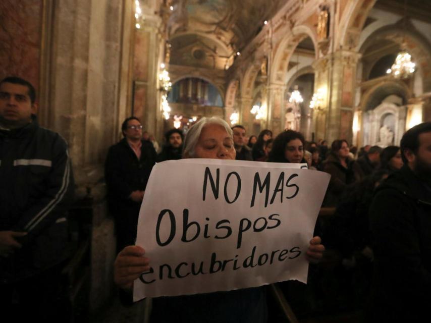 Una manifestane sosteniendo un letrero durante una misa en Santiago de Chile.